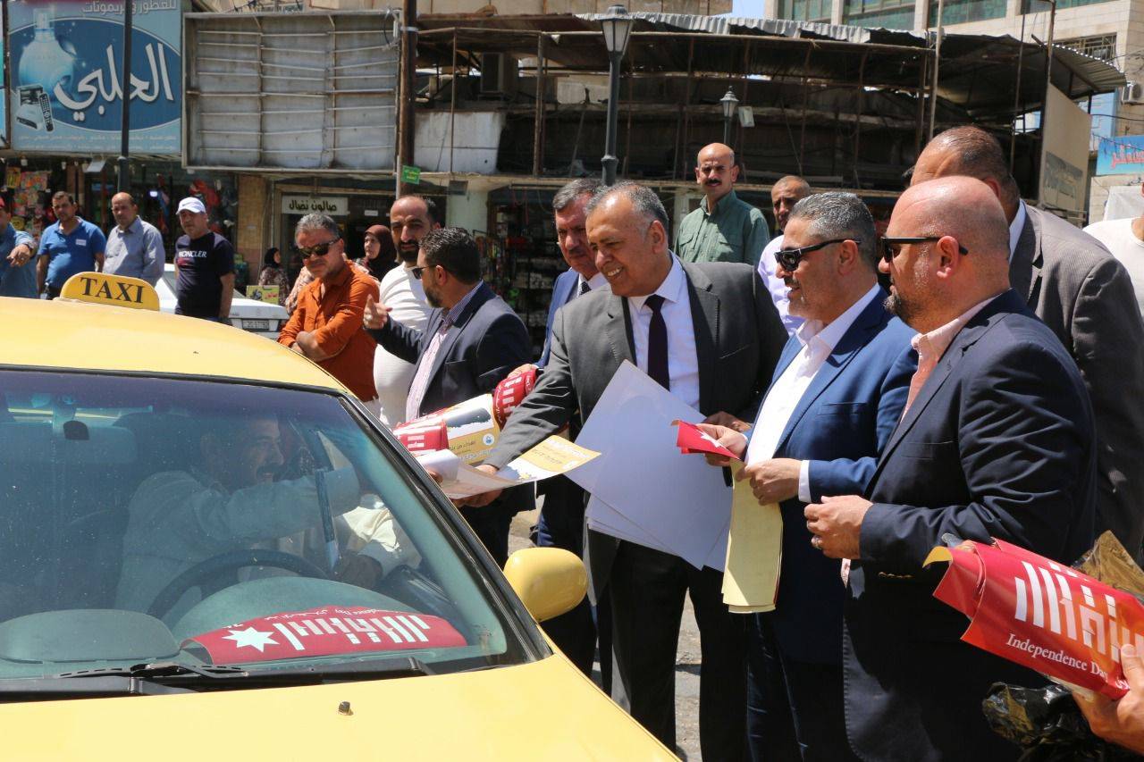 بحضور المحافظ الجبور .. بلدية الزرقاء تنفذ مبادرة لتوزيع شعار الاستقلال وصور الملك واعلام الاردن 